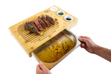 Bamboo carving board with draining tray, sliced steak, and three small condiment bowls