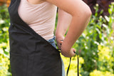 Person tying a black kitchen apron outdoors in a garden setting