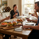 Friends enjoying burgers and wine at a wooden dining table with bamboo serving board.
