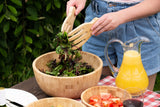Bamboo wooden salad bowl set with servers, fresh greens, outdoor picnic setup