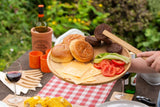 Large bamboo wooden serving tray with burger buns, cheese, lettuce, tomato, and grilled patties