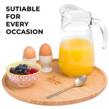 Large bamboo wood serving tray with orange juice, eggs, berries, and a spoon