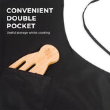 Black kitchen apron with double pocket holding a bamboo utensil, ideal for cooking storage.