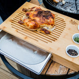 Roast chicken on a bamboo carving board with drip tray, herbs and peppercorns
