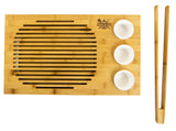 Bamboo carving board with grooves, three white ceramic bowls, and matching bamboo tongs