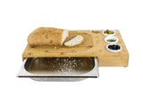 Bamboo bread cutting board with crumb tray, sliced bread, olives, and dipping bowls