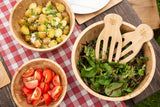 Three bamboo wooden salad bowls with mixed salad, tomatoes, and potato salad, on plaid tablecloth