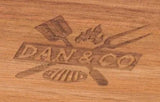 Engraved Dan & Co logo with grill utensils on natural acacia wood serving tray surface