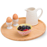Large bamboo wooden serving tray with eggs, ceramic jug, and bowl of fresh berries