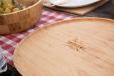 Large bamboo wooden serving tray on picnic table with salad bowl and checkered cloth