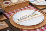 Large bamboo wooden serving tray with white plate, cutlery, and chopsticks on a picnic table