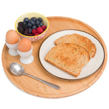 Large round bamboo wooden serving tray with breakfast, including toast, eggs, and mixed berries.
