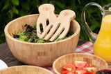 Bamboo wooden salad servers set in a matching bamboo salad bowl with fresh greens outdoors